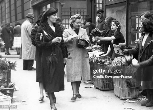 Des vendeuses de muguet proposent des bouquets aux passantes près de la Gare Saint-Lazare le 1er mai 1940 à Paris, France.