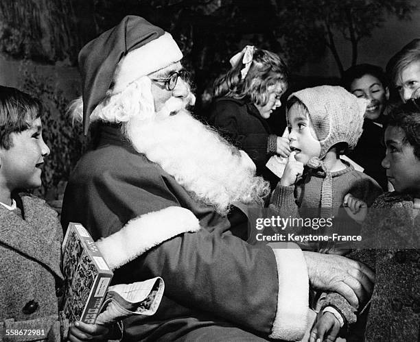 Une petite fille assise sur les genoux du Père Noël alors que des réfugiés de Tristan Da Cunha visitent un magasin le 21 novembre 1961 à Croydon,...