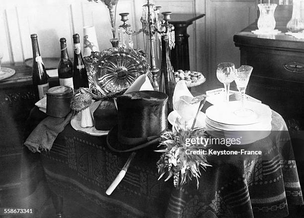 Vaisselle, verres en cristal, bouteilles de vin et un chapeau haut-de-forme posés sur une table.
