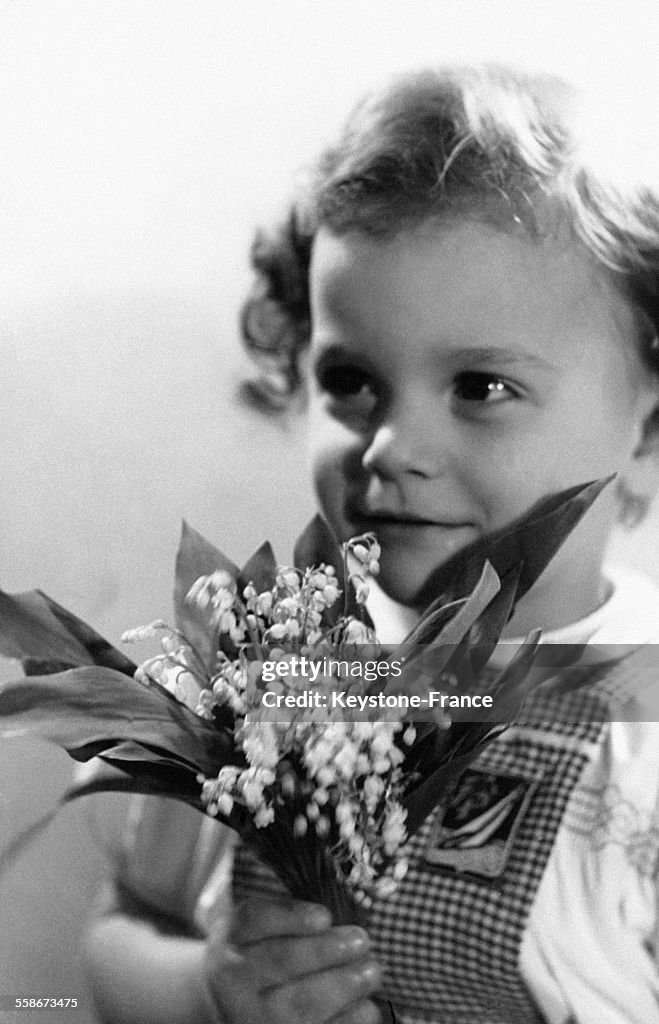 Un jeune enfant avec un bouquet de muguet