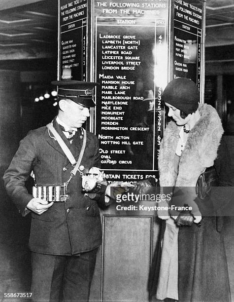 Une jeune femme achetant un ticket de métro à un employé de la compagnie sur une grande artère de Londres, Royaume-Uni le 9 décembre 1931.