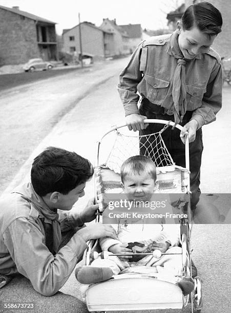 Deux boy scouts s'occupent d'un jeune enfant en poussette en l'absence de sa mère le 25 avril 1962 à Munich, Allemagne.