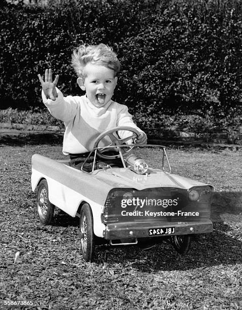 Un enfant de 2 ans conduit une voiture miniature en avril 1961.