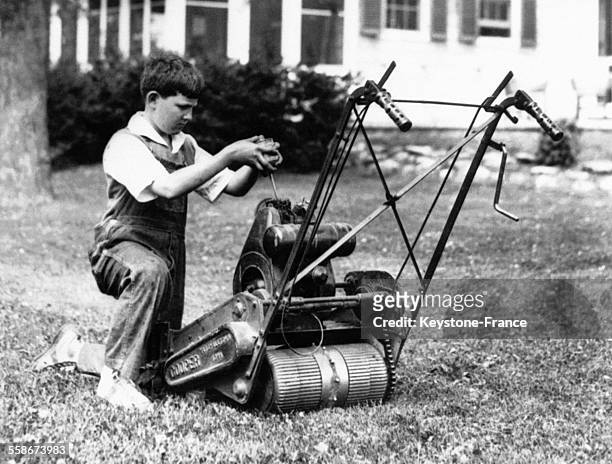 Guy Stillman examine la tondeuse à gazon sur le pelouse de la nouvelle résidence de sa mère, Mrs Stillman McCormick le 24 mai 1932 à Barrington, IL.