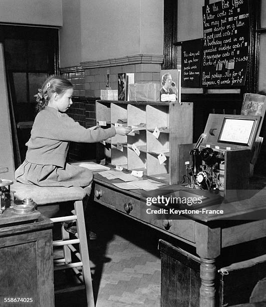 Une élève de la Bell Lane Infants School apprend le fonctionnement d'un bureau de poste et à envoyer le courrier dans la poste de l'école à Hendon,...