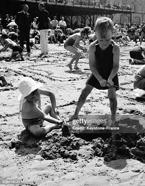 Deux jeunes garçons jouent dans le sable sur la plage.