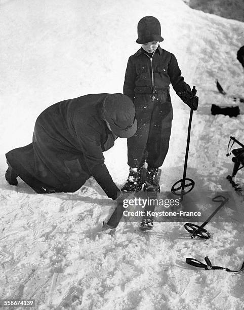 Shaun Plunket, jeune membre de la haute société britannique, laisse sa gouvernante fixer ses skis à Saint-Moritz, Suisse.