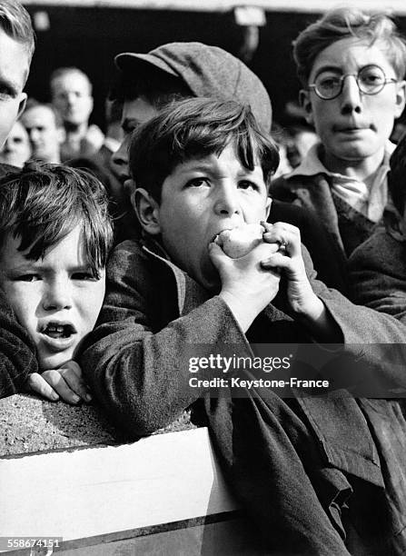 De jeunes supporters observent un événement sportif avec attention depuis les gradins.