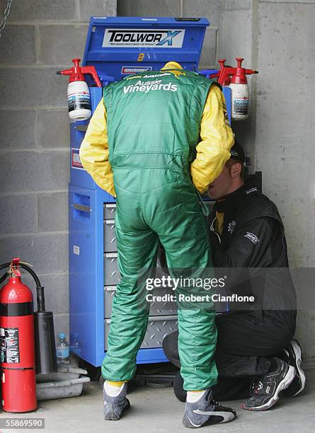 Marcus Marshall of Team Australia has his racing suit zipper repaired by a team member during practice for the Bathurst 1000 which is round ten of...