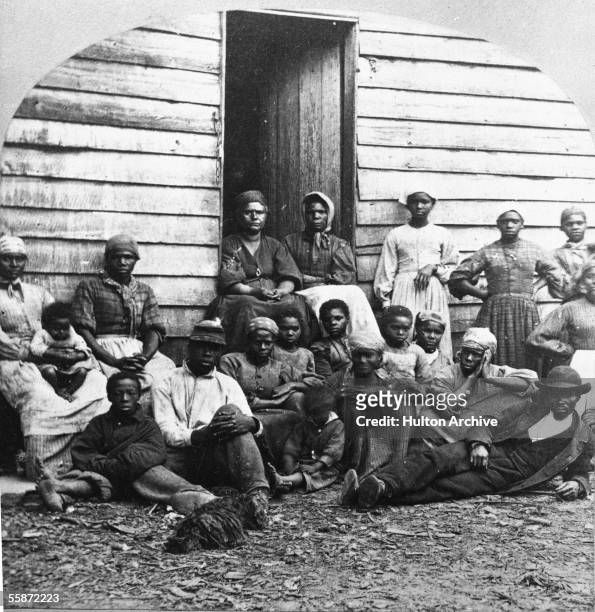 Portrait of Civil War 'contrabands,' fugitive slaves who were emancipated upon reaching the North, sitting outside a house, possible in Freedman's...