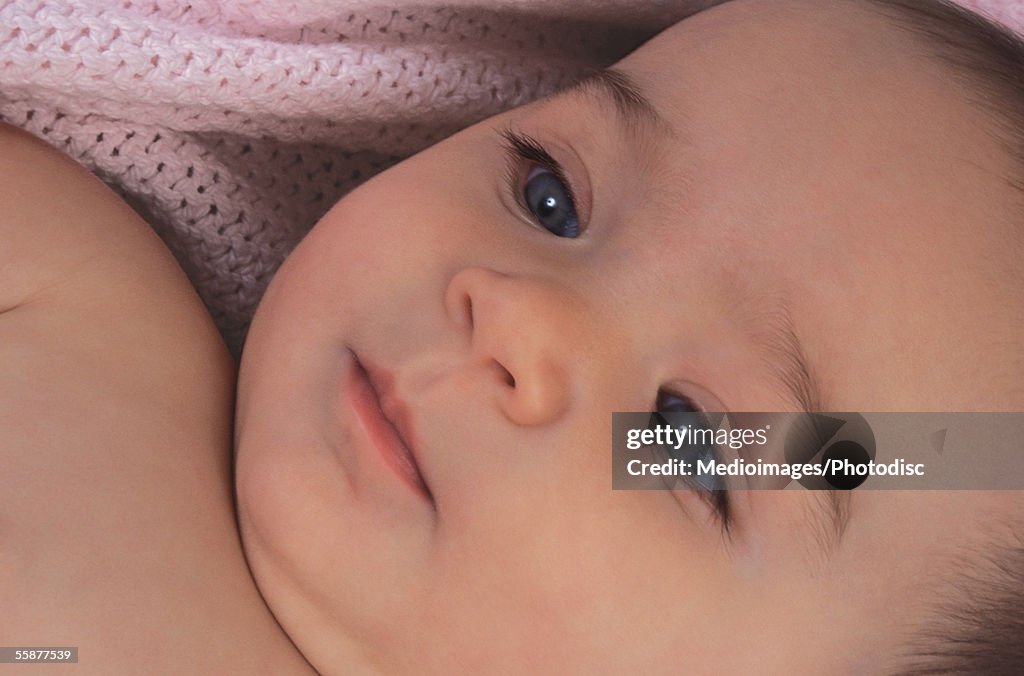 Baby girl (6-9 months) lying, elevated view, close-up