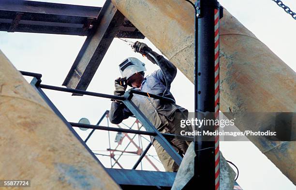 welder repairing beam on construction site, low angle view - steel worker stock pictures, royalty-free photos & images