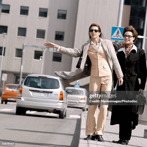 two businesswomen hailing a vehicle - foulard vent photos et images de collection