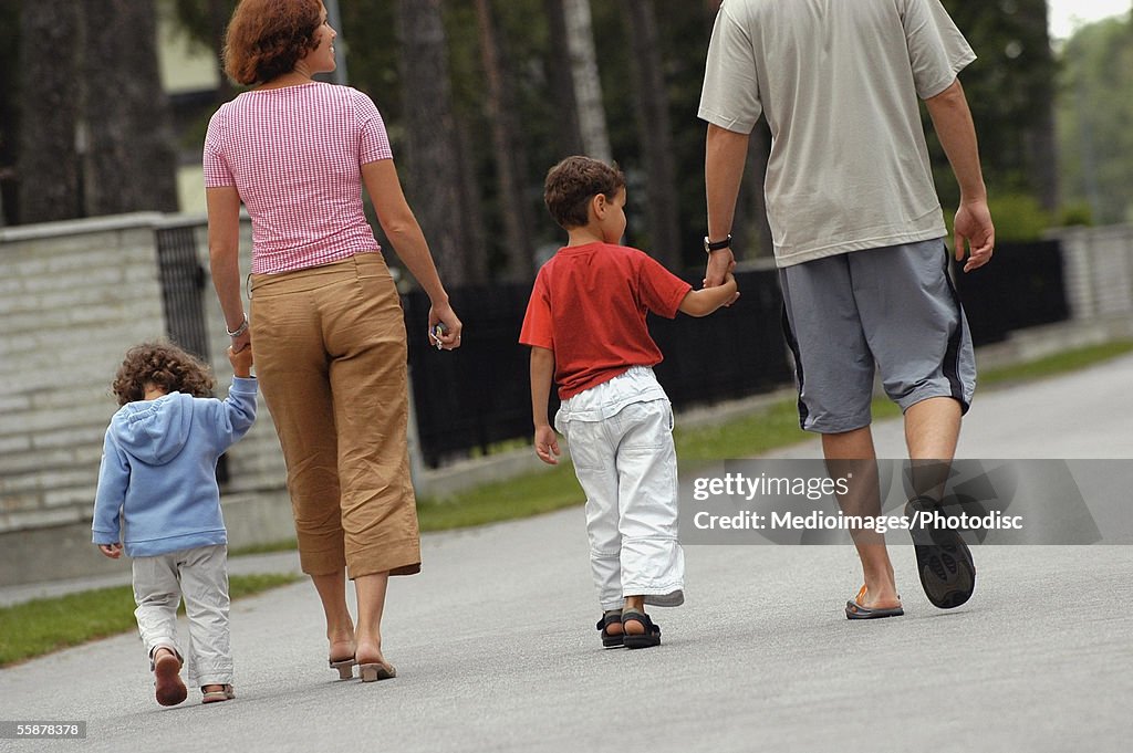 Rear view of parents walking with their two children