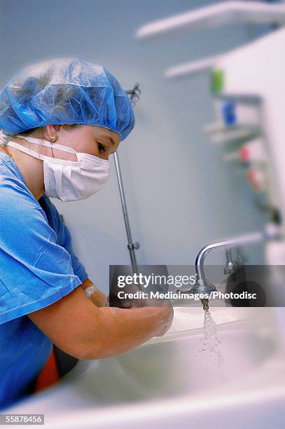 side profile of a female surgeon washing her hands - surgical mask profile stock pictures, royalty-free photos & images