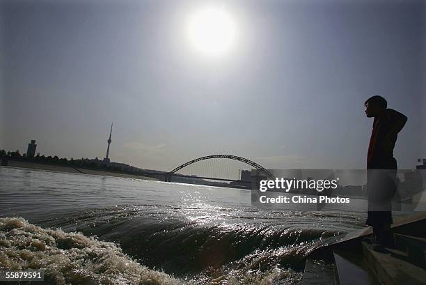 Chinese man watches as floodwater flows at an infall where the Hanjiang River joins the Yangtze River on October 7, 2005 in Wuhan of Hubei Province,...