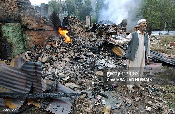An Indian Kashmiri man stands amid debris of burnt shops following a powerful earthquake measuring at least 7.6 on the Richter scale, in Uri some 100...