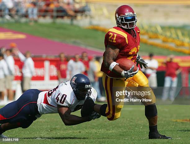 LenDale White of USC slips the tackle of John Mckinney of Arizona during the third quarter at the Los Angeles Colliseum on October 8, 2005 in Los...