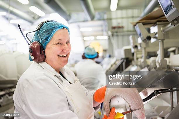 Worker holding fish meat and knife in industry