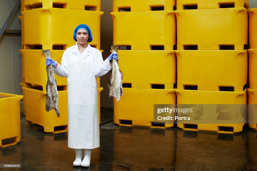 Female worker holding fish in factory