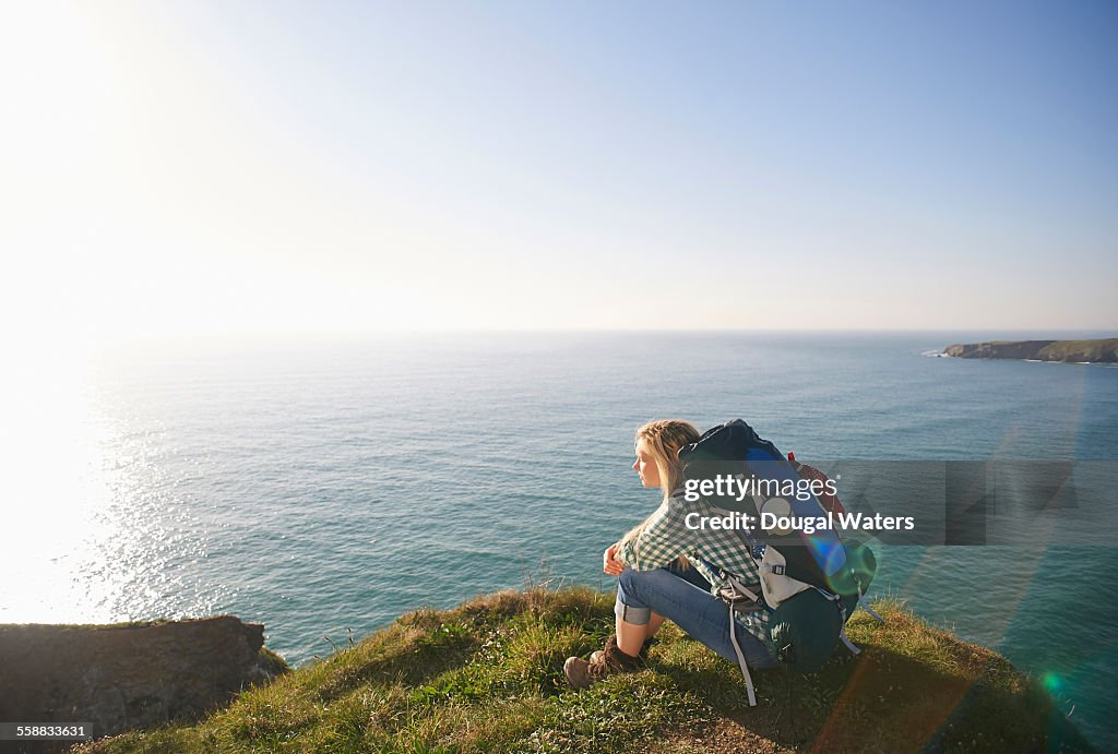 Female hiker sitting atop Atlantic cliff