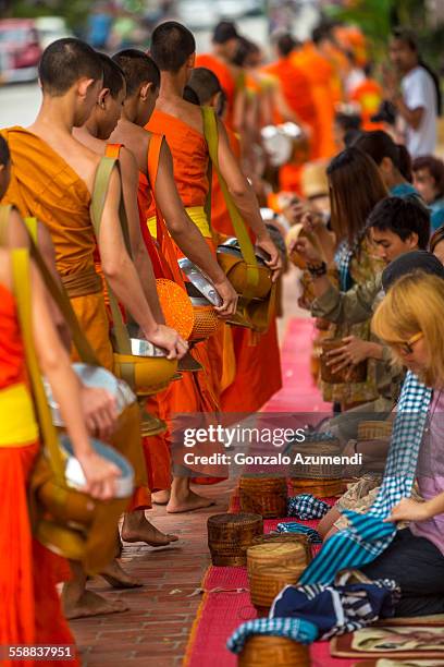 monks collecting alms in luang prabang - elemosina oggetto religioso foto e immagini stock