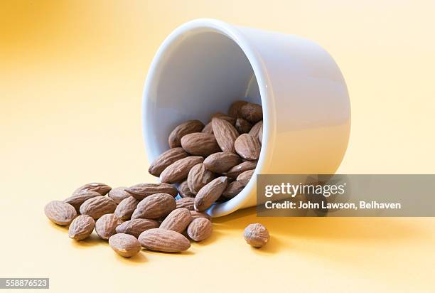 almonds spilling from a white dish - food coloured background stock pictures, royalty-free photos & images
