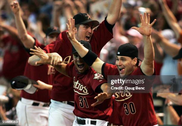 Pitcher Chad Qualls, Charles Gipson and Luke Scott of the Houston Astros come out of the dugout to celebrate after Chris Burke hit a solo home run to...