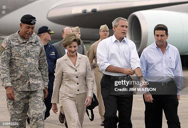 New Orleans, UNITED STATES: US President George W. Bush rolls up his sleeves as he walks with First Lady Laura Bush , Plaquemines Parish President...