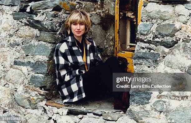 English television presenter Selina Scott in the window of a run-down cottage, circa 1985.