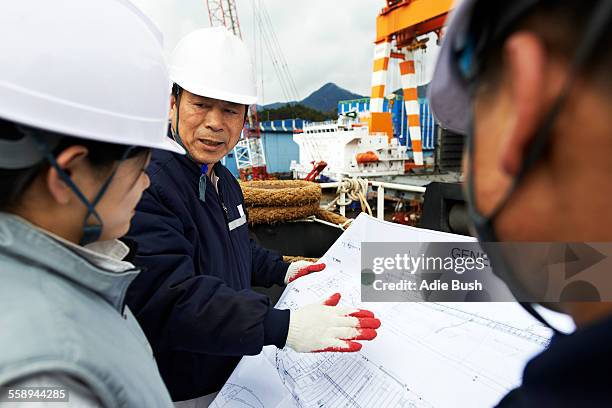 workers looking at plans at shipyard, goseong-gun, south korea - shipbuilder stock pictures, royalty-free photos & images