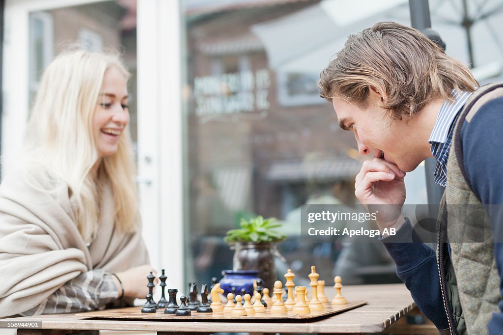 Happy couple playing chess at cafeteria backyard