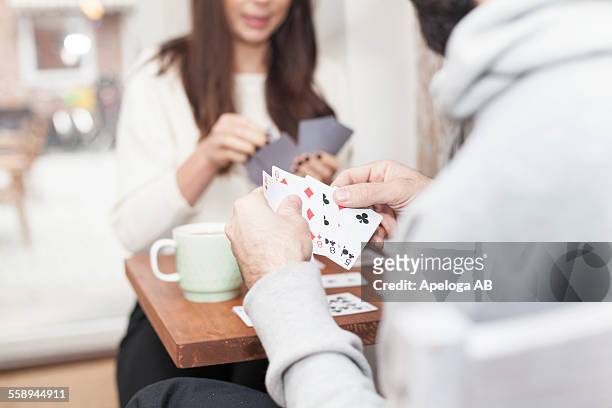 midsection of couple playing cards in coffee shop - winning hand stock pictures, royalty-free photos & images