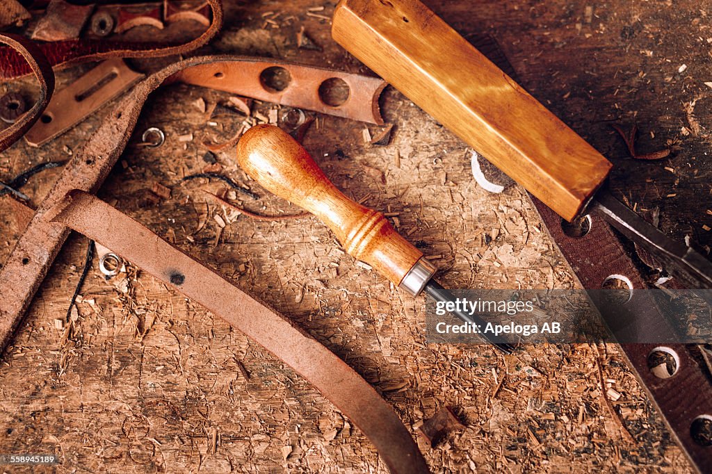 Close-up of tools and waste leather on table