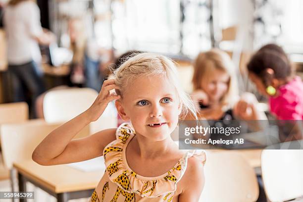 girl scratching head while looking away in classroom - sich am kopf kratzen stock-fotos und bilder