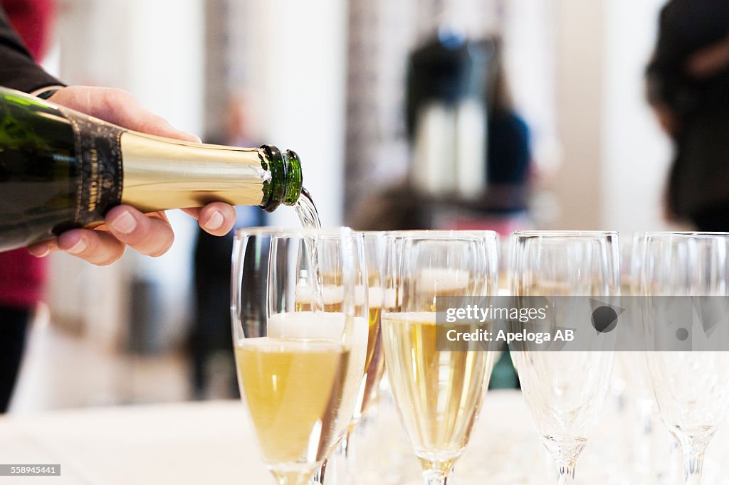 Cropped image of person pouring champagne in flutes