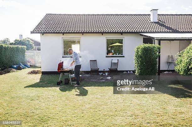 full length of man grilling food outside house - rooftop bbq stock pictures, royalty-free photos & images