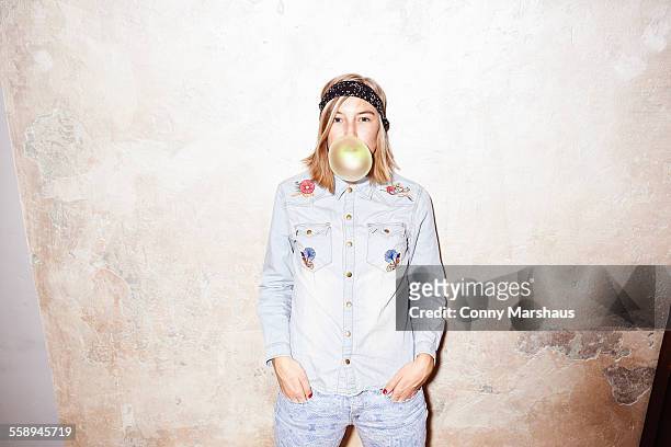 studio shot of young woman blowing yellow bubble gum bubble - frauenpower stock-fotos und bilder