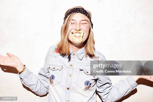 studio shot of young woman with mouth covered in yellow gum bubble - bubble gum stock pictures, royalty-free photos & images