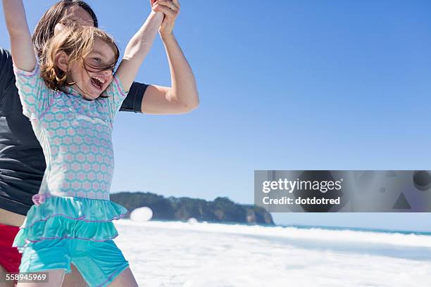 mother and daughter jumping in sea, hot water beach, bay of islands, new zealand - bay of islands new zealand stock pictures, royalty-free photos & images