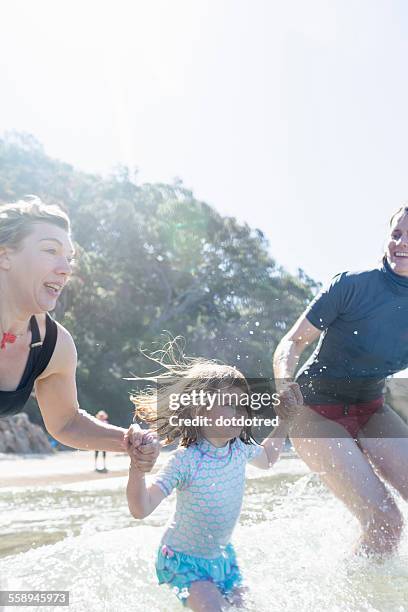 two women and girl running into sea, hot water beach, bay of islands, new zealand - bay of islands new zealand stock pictures, royalty-free photos & images