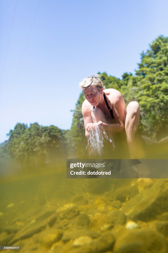 Woman splashing face with water in river, Coromandel Peninsula, North Island, New Zealand