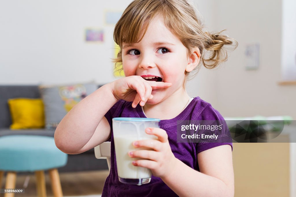 Girl holding glass of milk at home