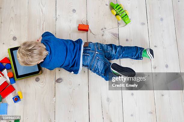 boy playing with digital tablet on wooden floor - allongé sur le devant photos et images de collection