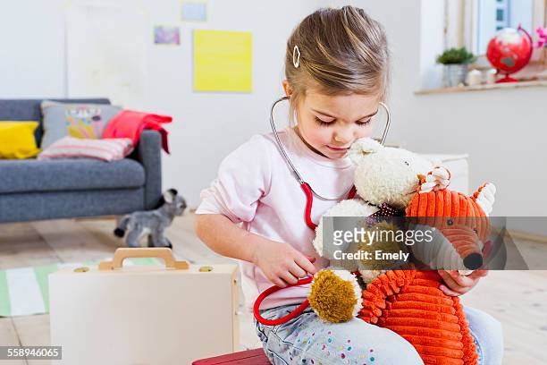 girl playing doctor to soft toys - doctor children stock-fotos und bilder