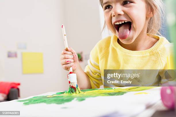 girl painting and sticking out tongue - blonde girl sticking out her tongue stock pictures, royalty-free photos & images