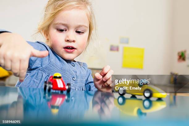 girl playing with toy cars at home - blonde fille photos et images de collection