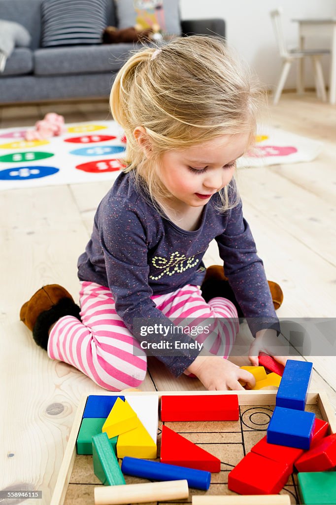 Girl playing with building blocks at home