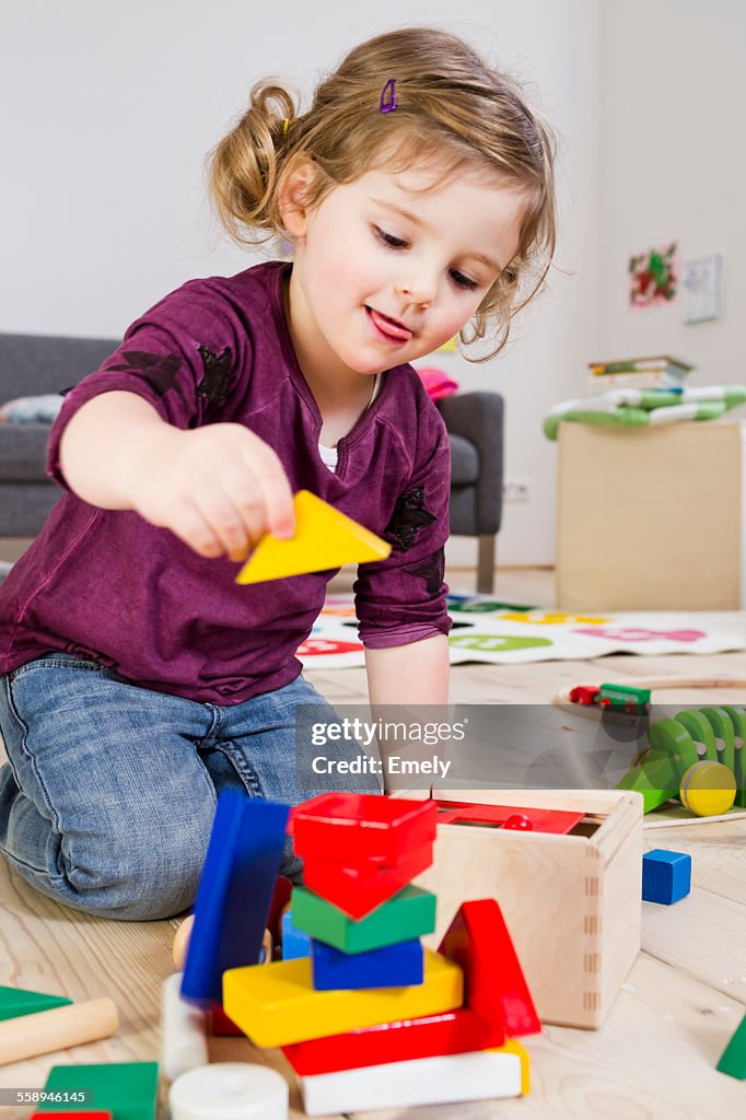 Girl playing with building blocks at home