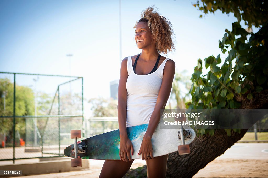 Portrait of young woman holding skateboard